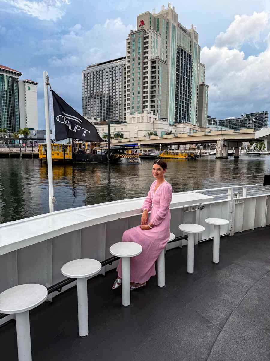 Amy sitting on a seat at the bow of a sunset boat cruise with the Tampa Bay skyline in the distance
