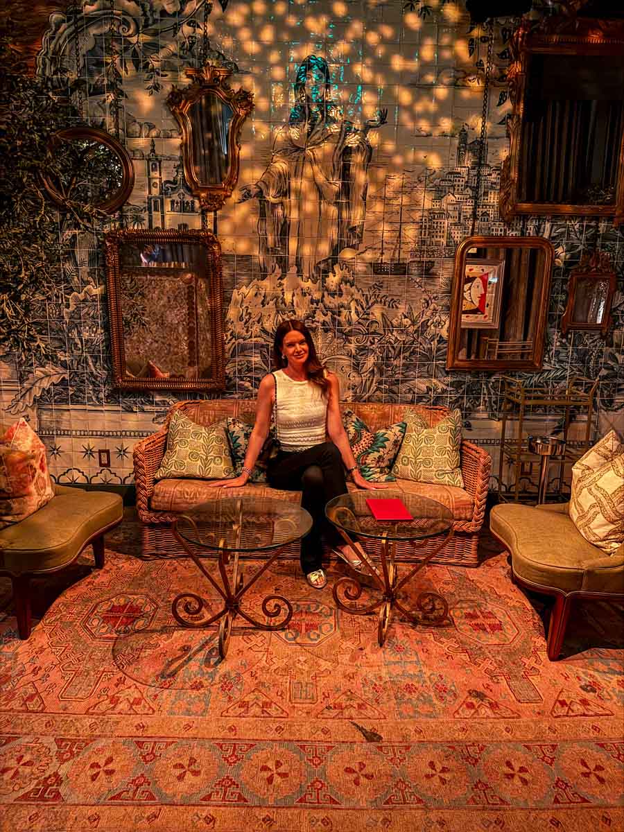Amy on an ornate sofa inside a dimly lit restaurant with Spanish style tiles on the wall and a patterned rug on the floor