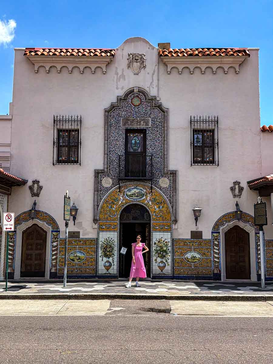 Amy in a pin dress standing in front of a spanish-style restaurant with ornate and colourful tiling around the door and windows