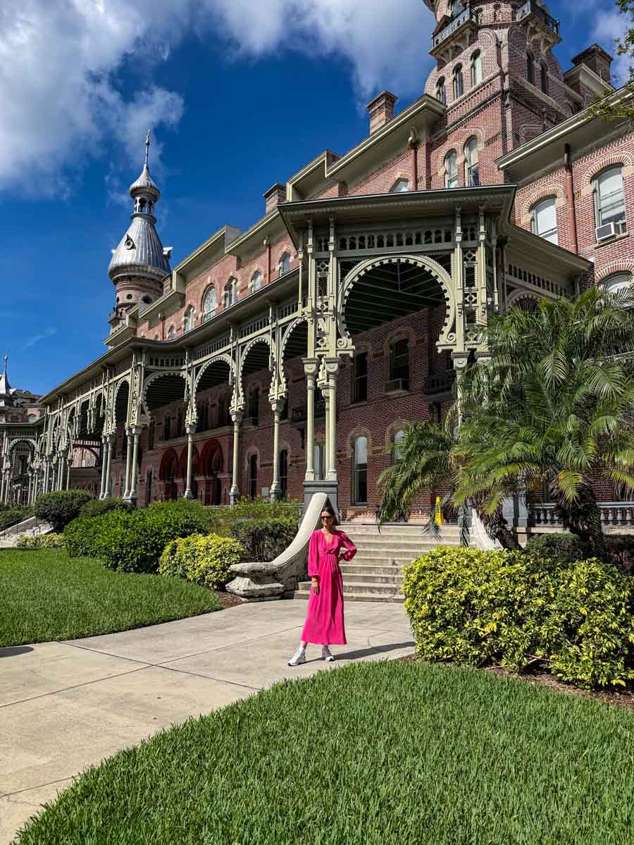 Amy in a long pink dress standing on a path in front of an ornate building with details porch and minarets in the distance. It's a sunny day with blue sky in Tampa Bay, Florida
