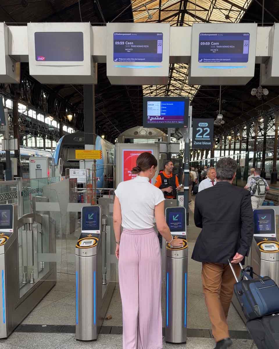 Amy at the train station gates ready to board the NOMAD train from Paris to Caen, France
